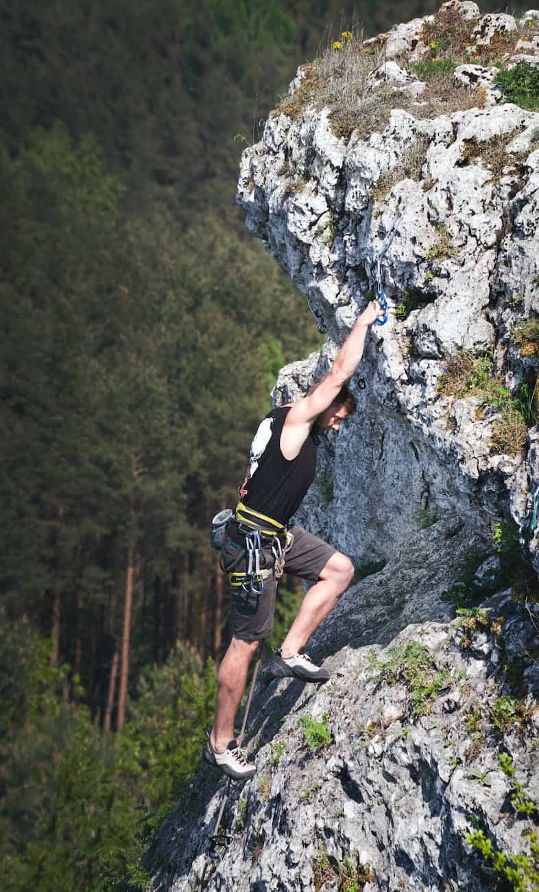 man wearing black tank top and brown shorts climbing rock/anxiety