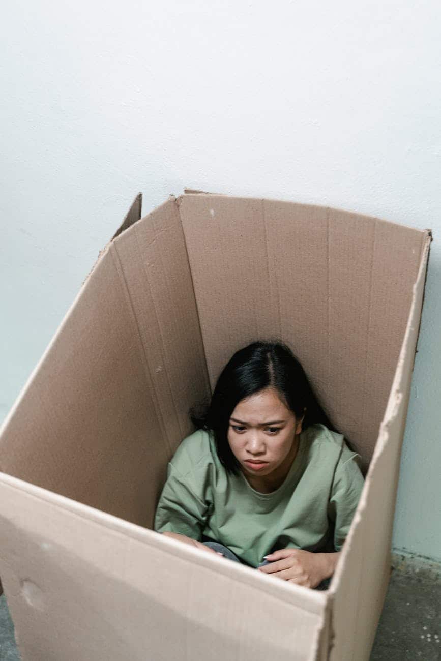 a fearful woman having claustrophobia in a cardboard box/fail or succeed