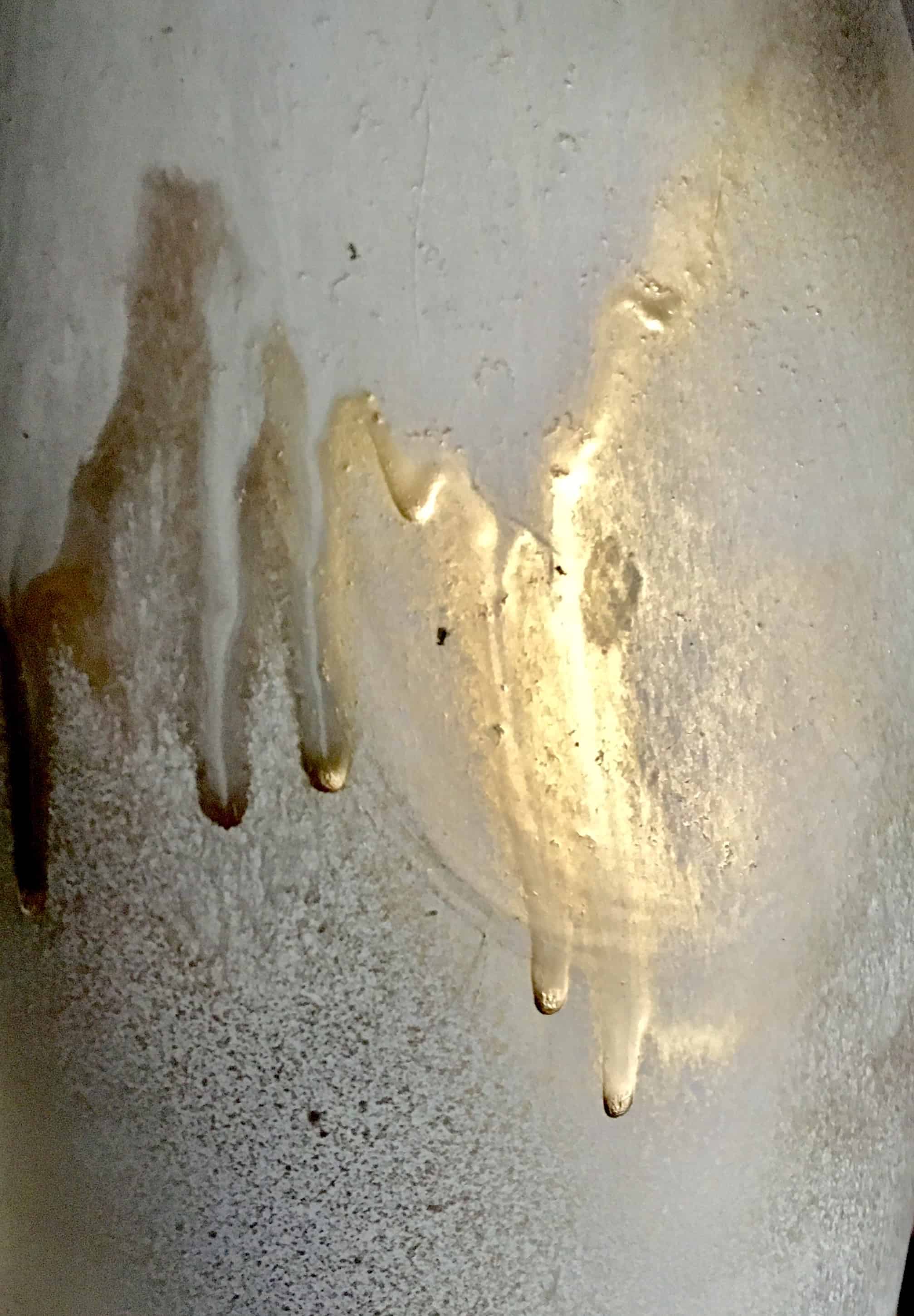 large white vase, about three feet high, painted white the painted over in spots with gold.