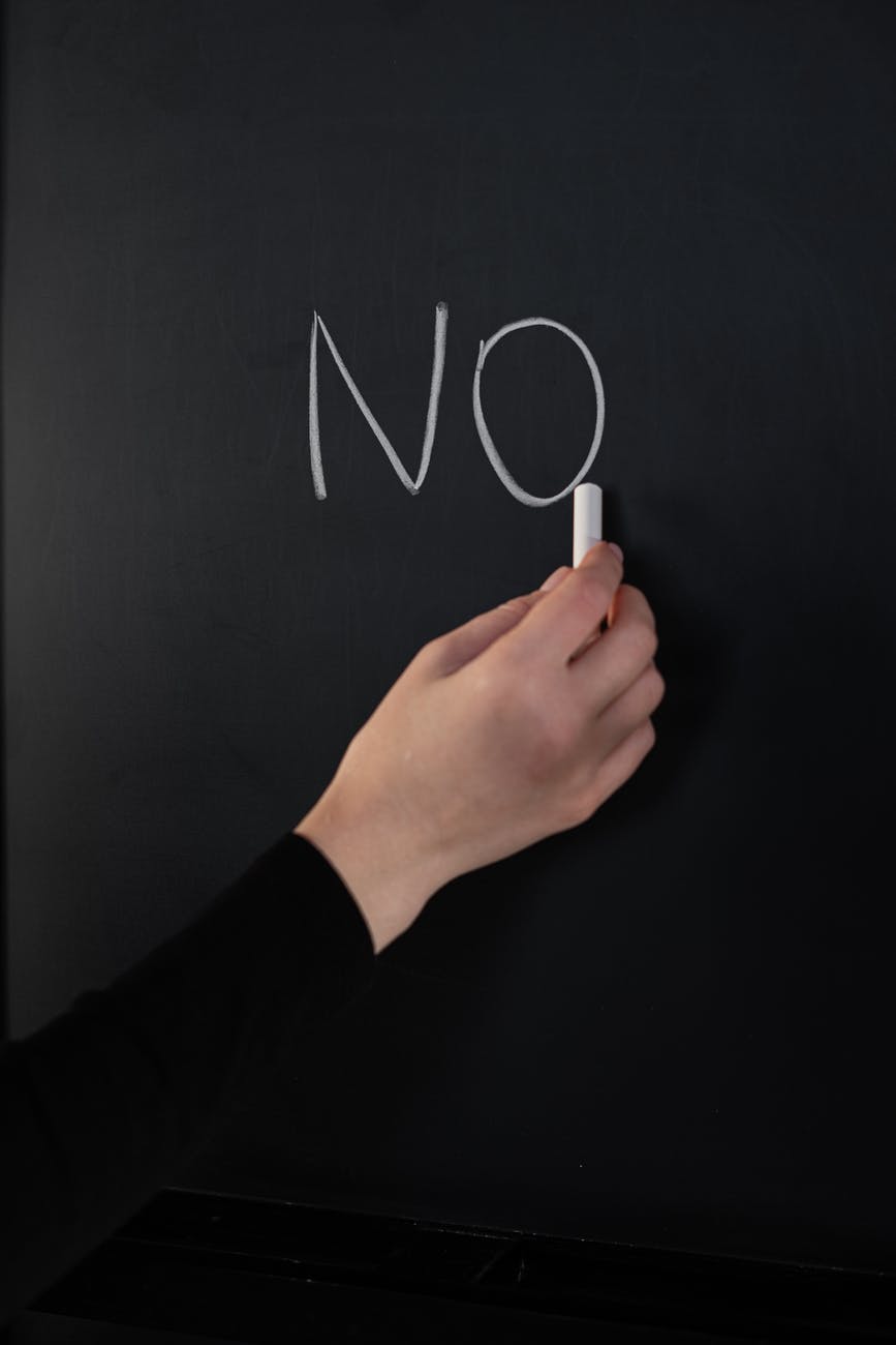 person holding white chalk that say "no"/saying not is OK