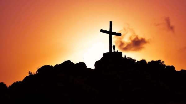 human standing beside crucifix statue on mountain/Easter
