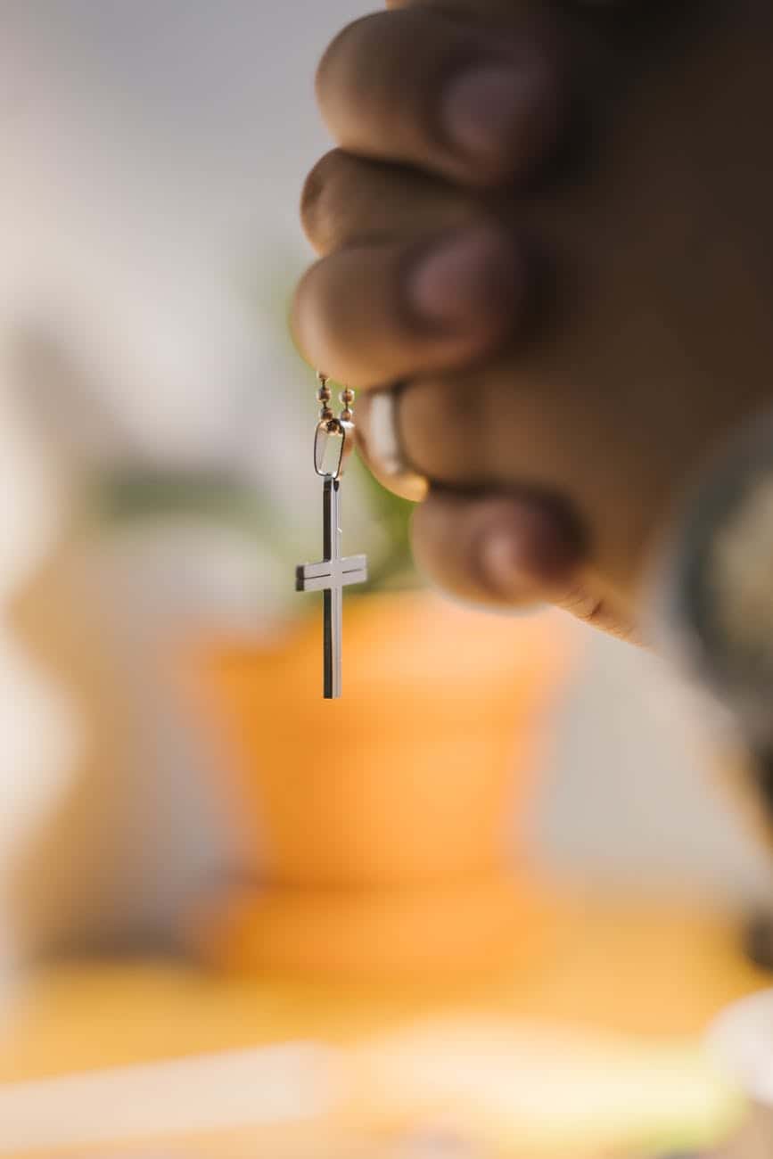 close up shot of a person holding a cross pendant/worry