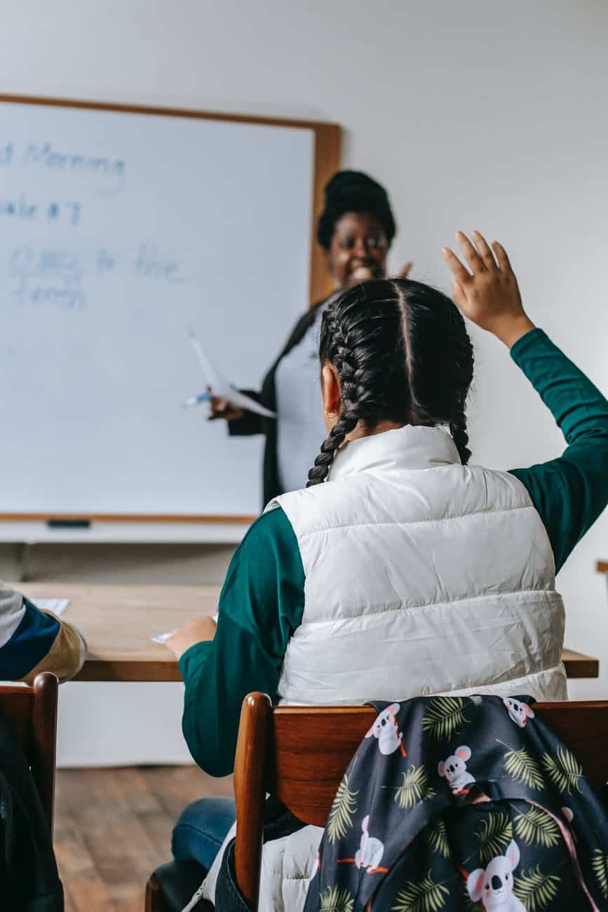 black female teacher looking at schoolgirl raising hand/make your faith your own