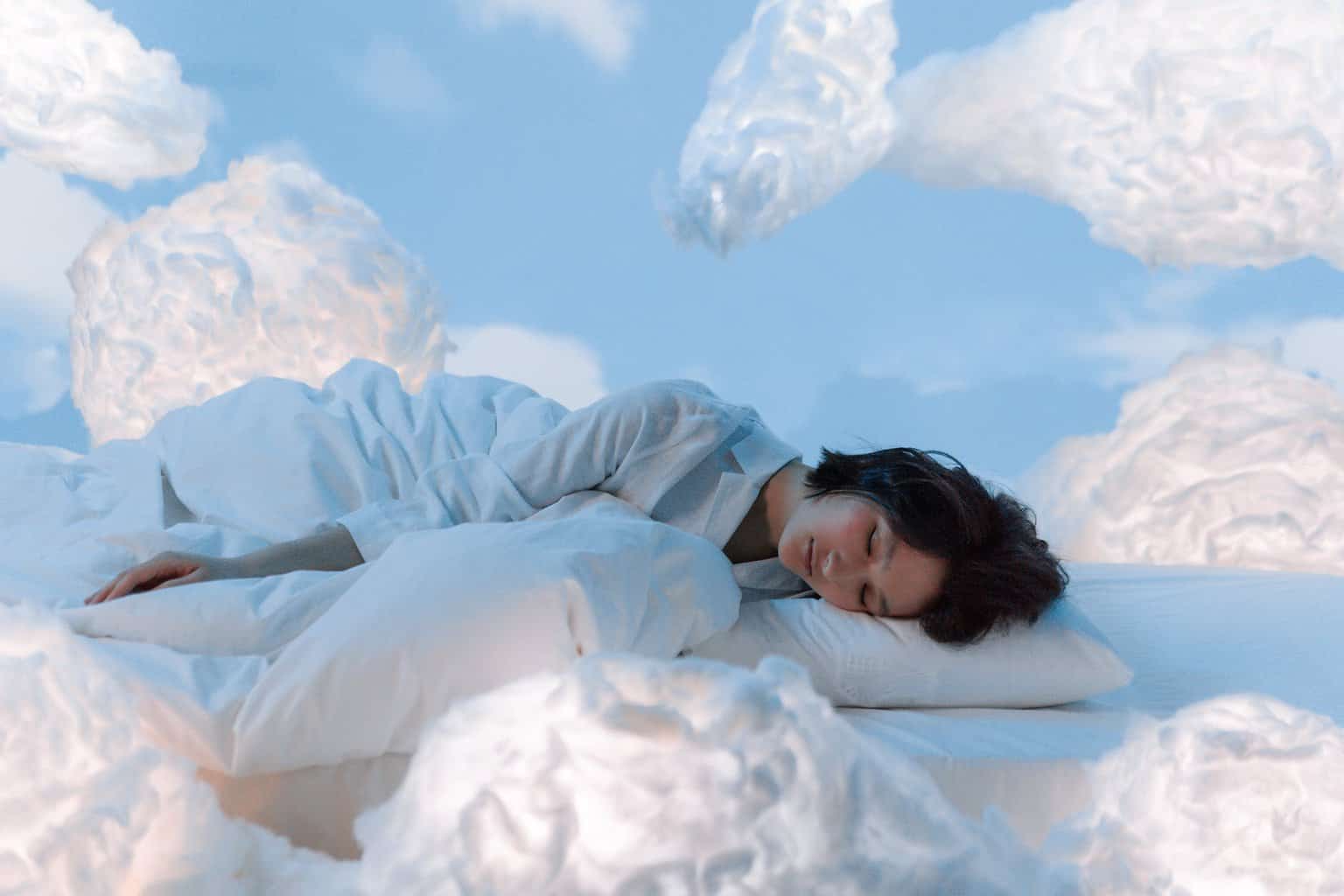 photo of a woman sleeping near fluffy clouds/dreams