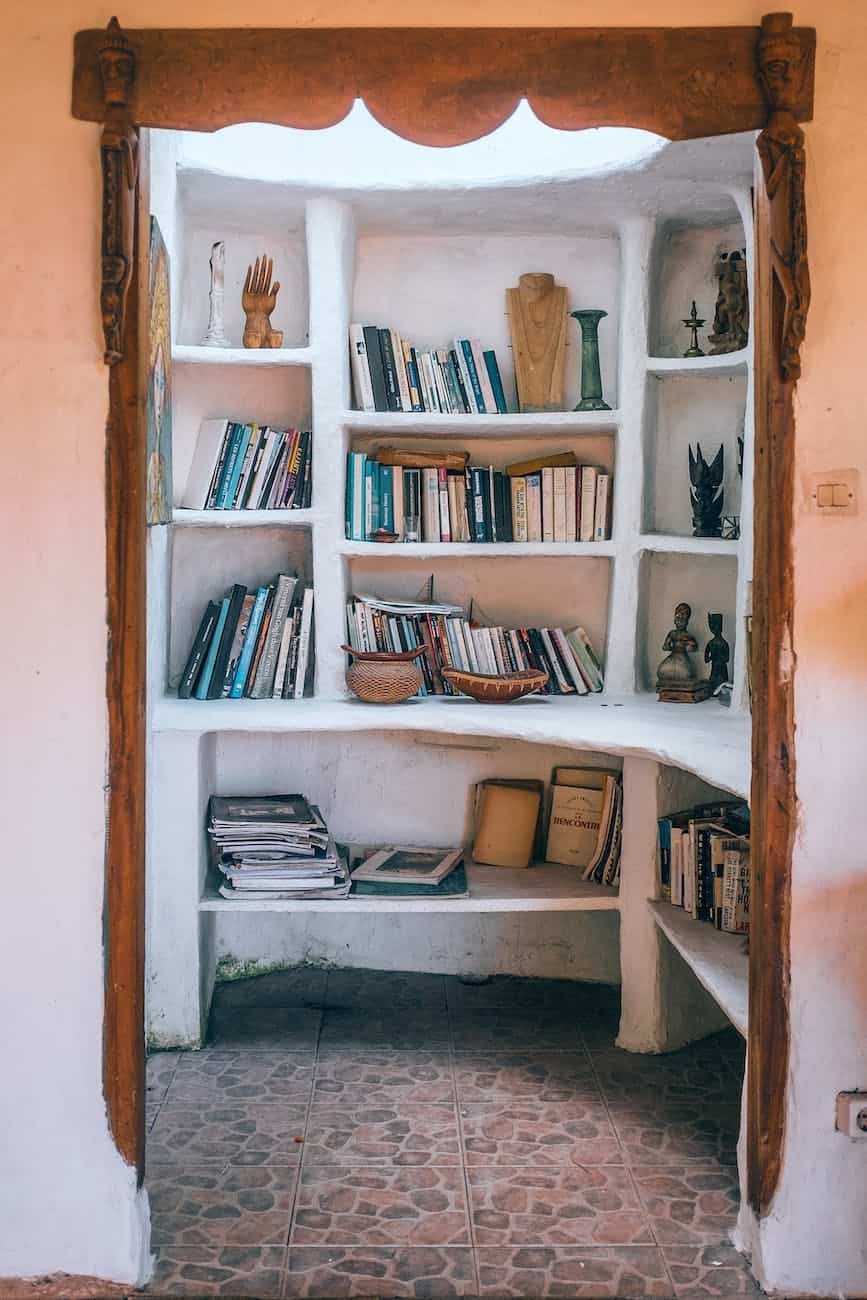 pexels-photo-4947110 | goodthoughtsgoodlives white shelves with various books and vases located in small room/personal spaces