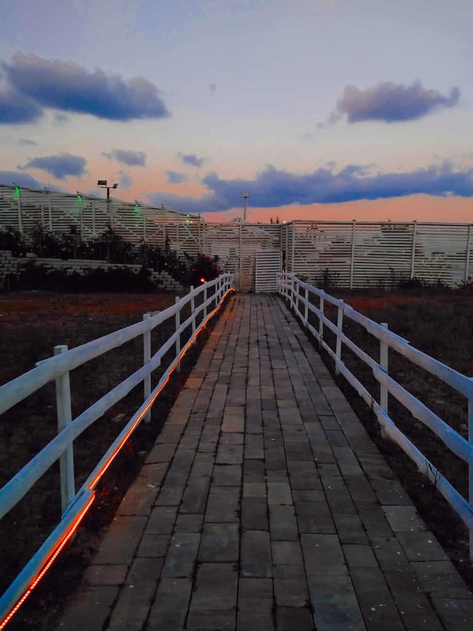 photo of pavement near white fences/personal space