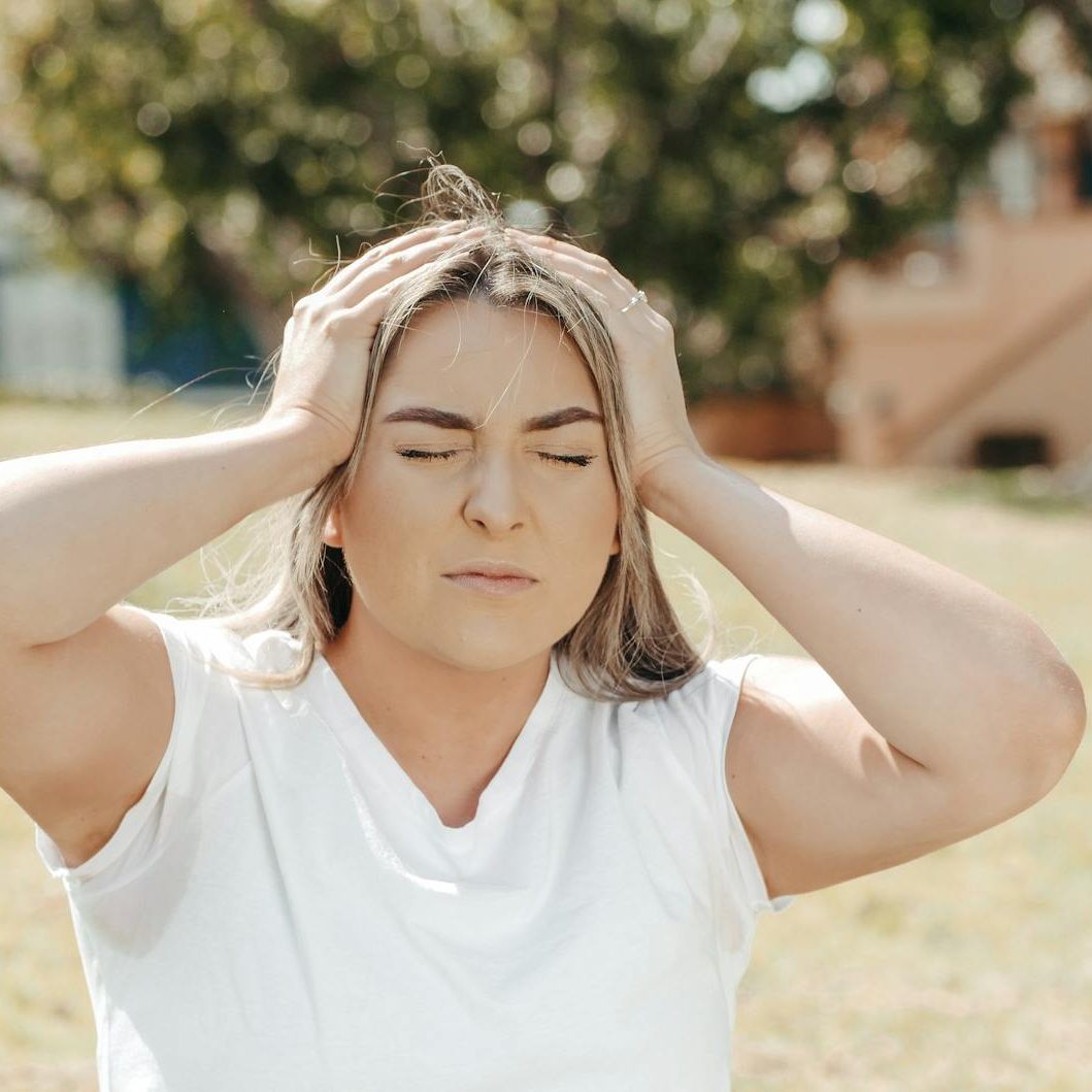 a woman holding her head while eyes closed/decisions