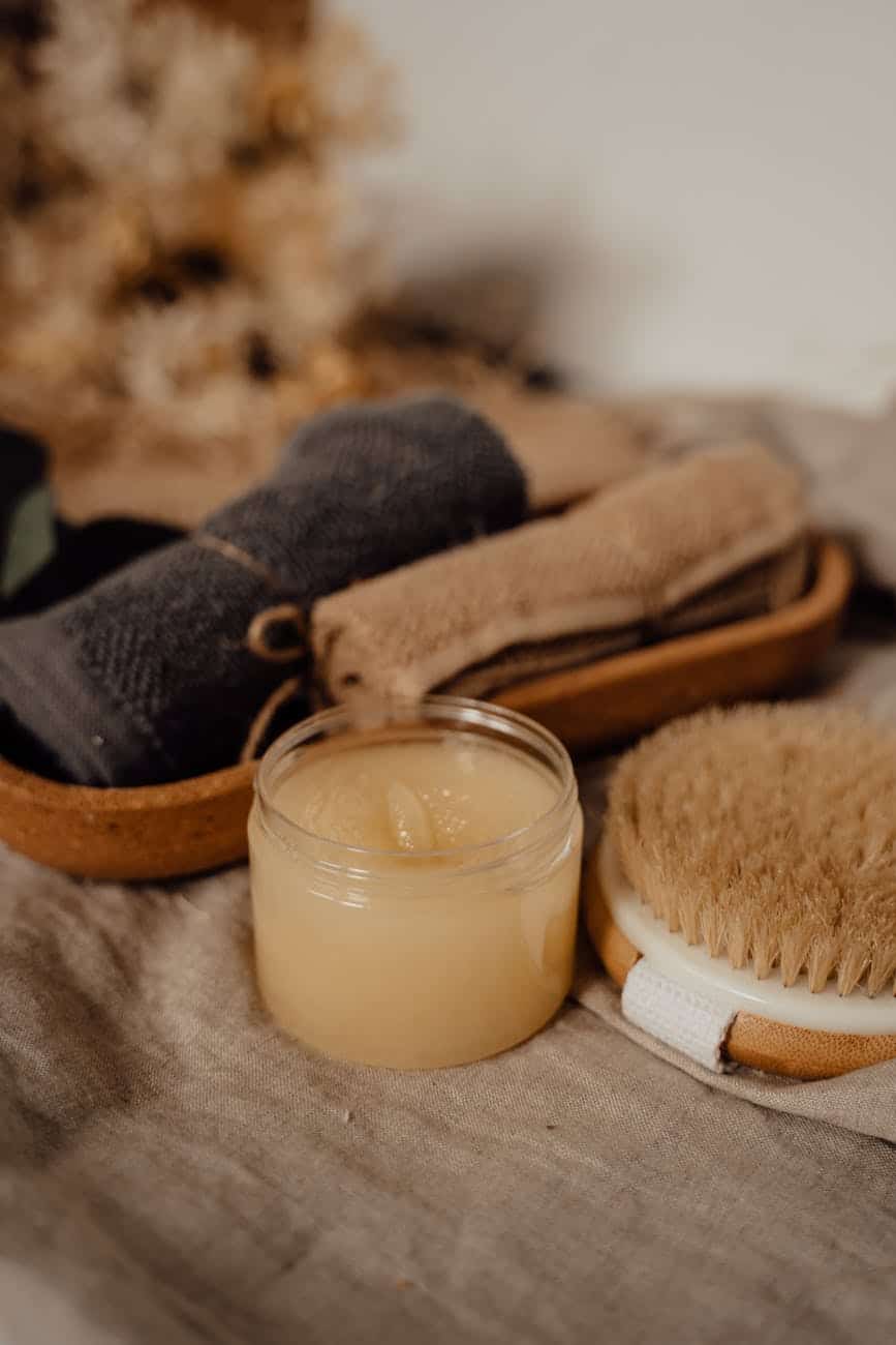 body scrub in plastic jar beside body brush/self-care