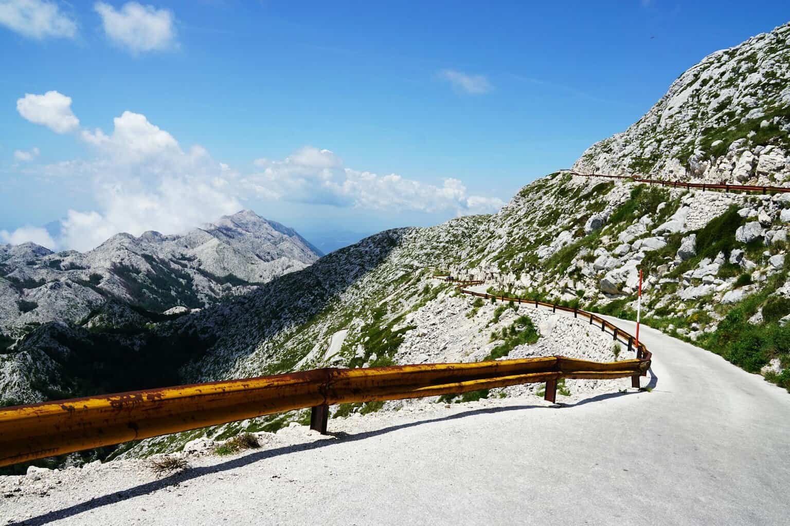 photo of narrow paved mountain road with barrier