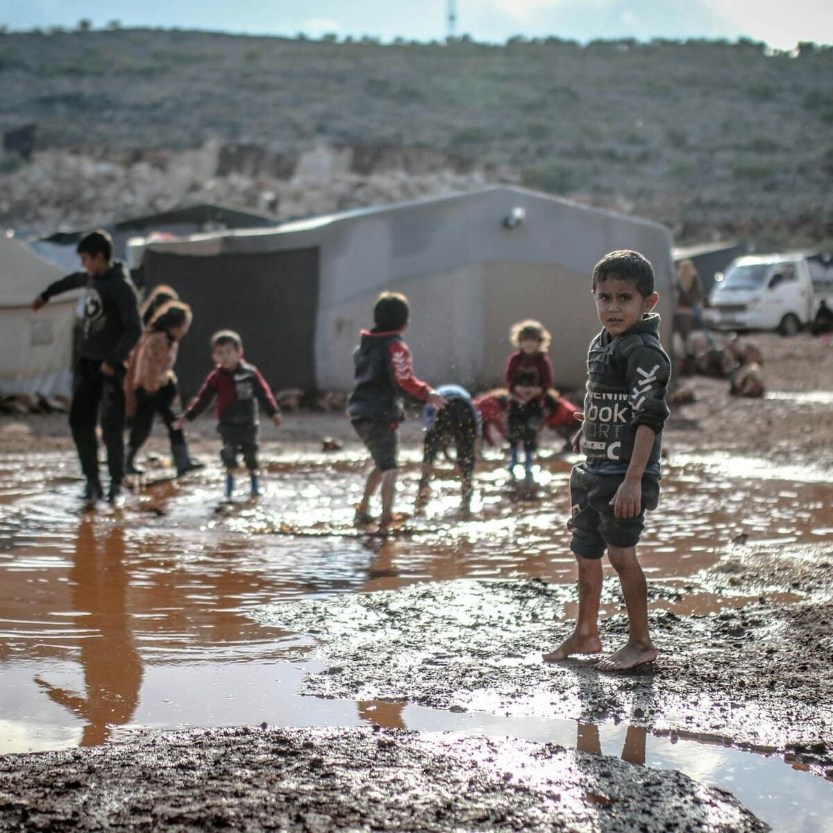 kids splashing water in puddle/struggles