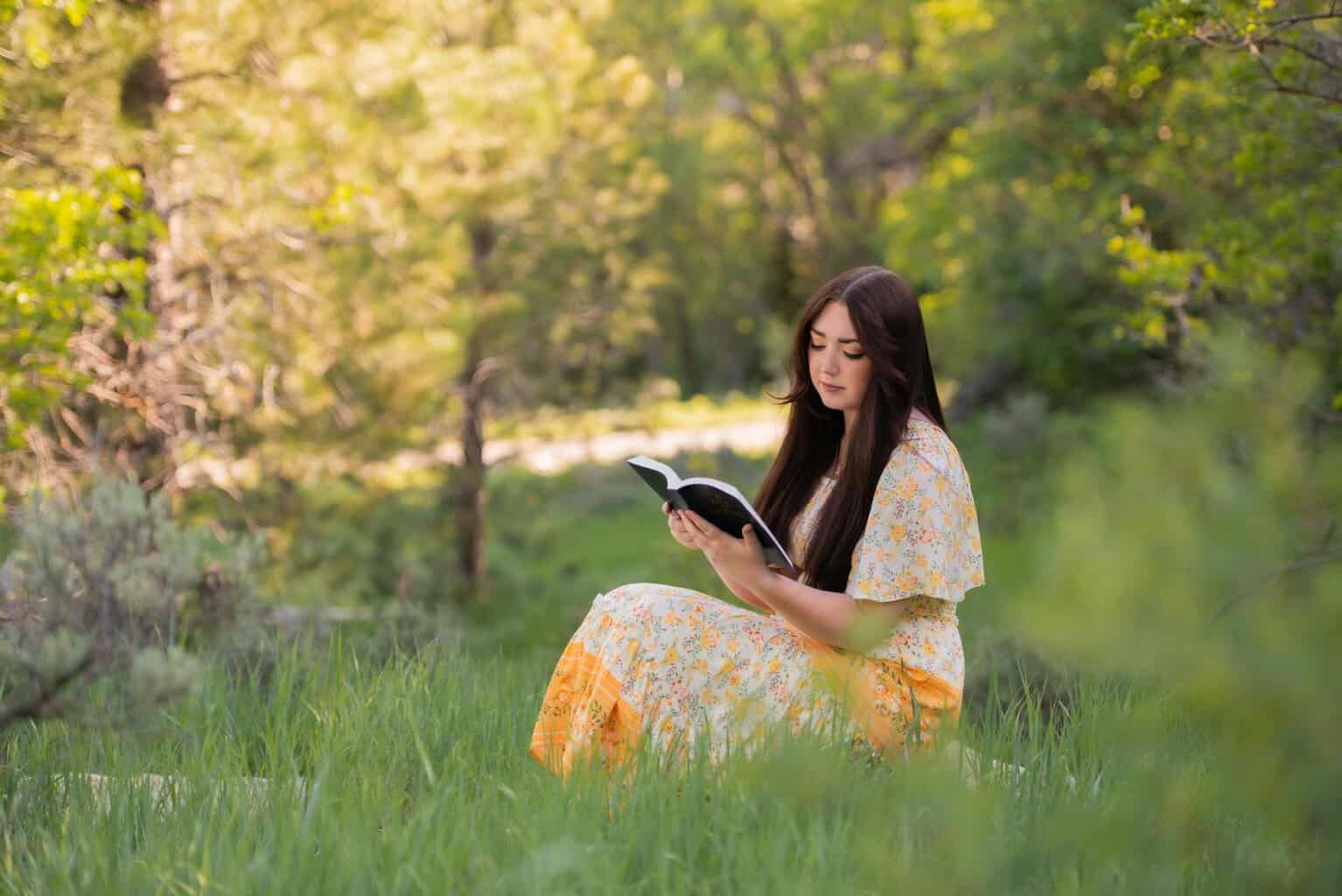 woman reading a book on green grass/pray