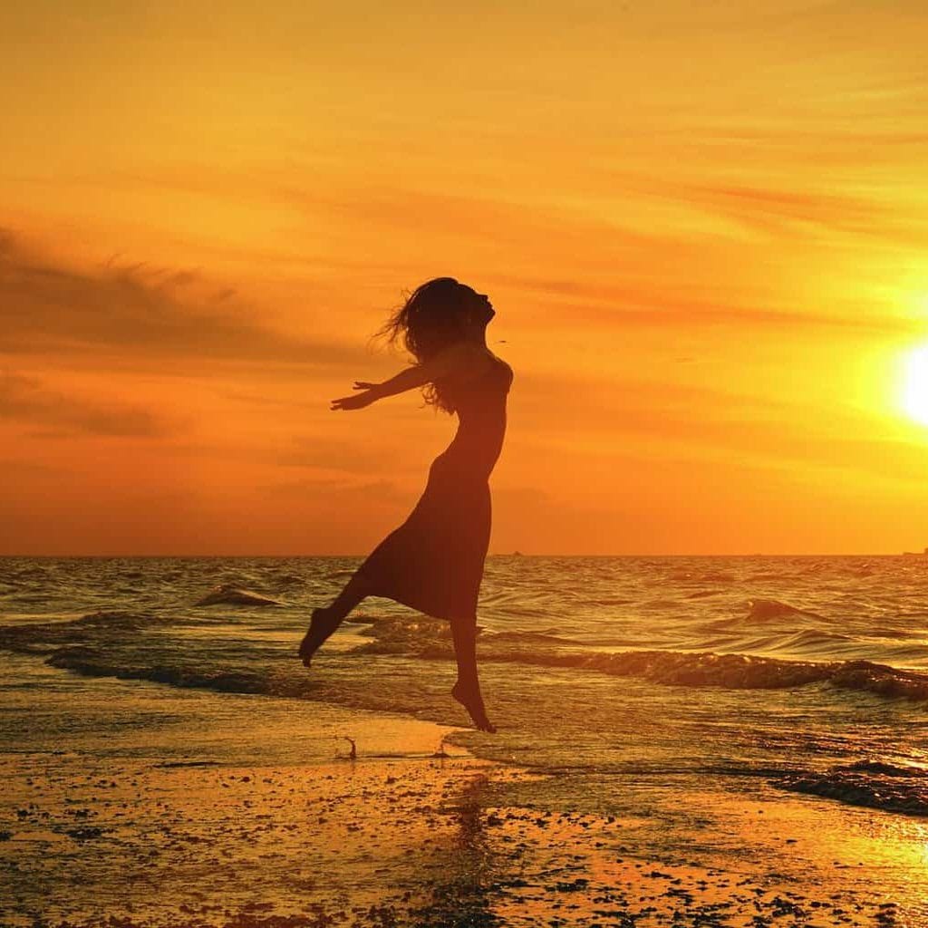 silhouette of unrecognizable woman jumping above sea beach at sunset/Stop waiting. Live your life.