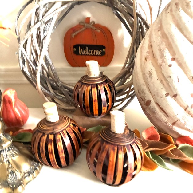 img_5915 | goodthoughtsgoodlives Small orange pumpkin wreath decor with a metal twig frame and candles on a shelf.