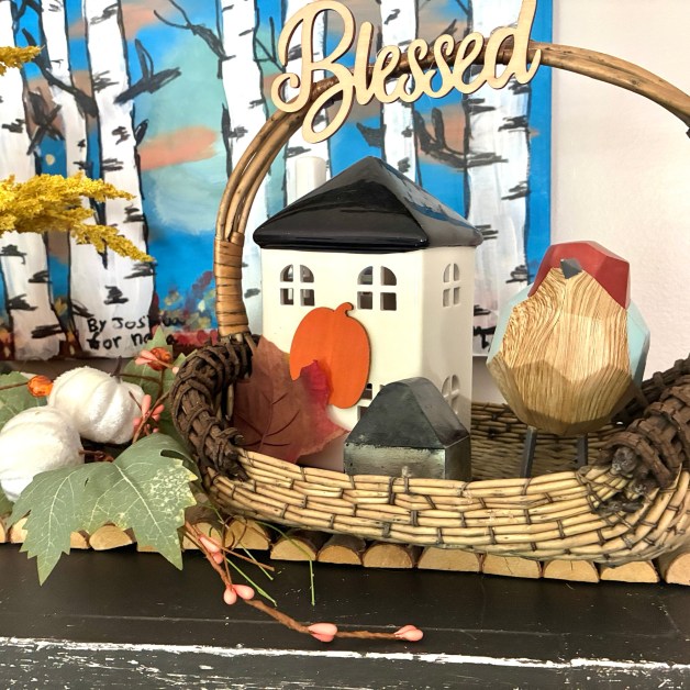 img_6030-1 | goodthoughtsgoodlives Decorative autumn display with a wicker basket, a small white house, orange leaves, and pink berries.