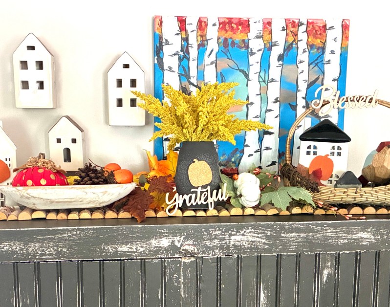 img_6034-2 | goodthoughtsgoodlives Autumn display featuring white ceramic houses, dried yellow flowers, pumpkins, and a birch-tree painting with the words 'Grateful' and 'Blessed'.